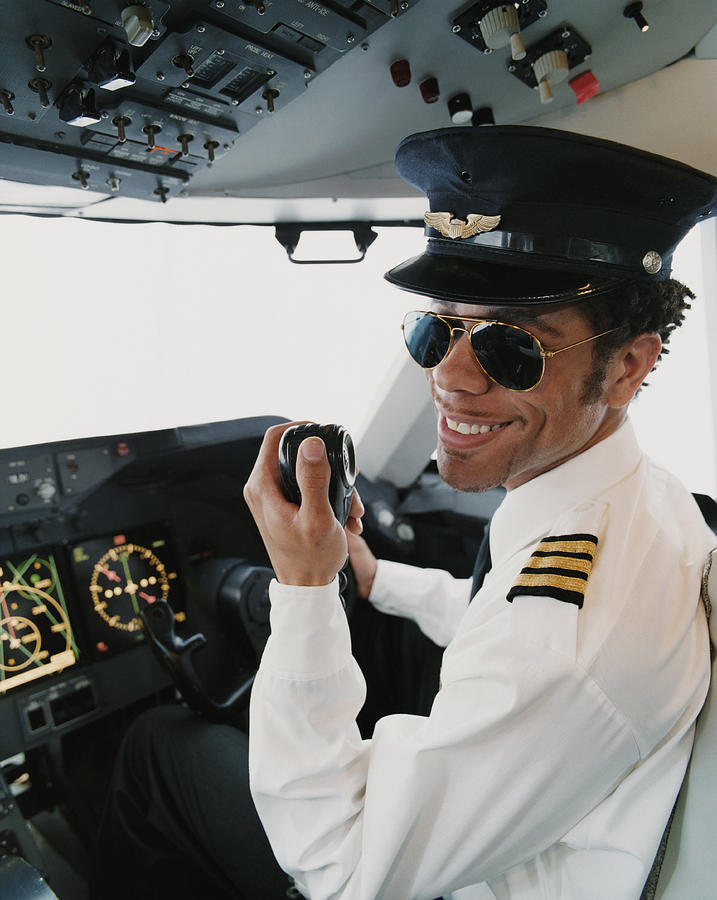 Portrait of a Pilot Sitting in the Cockpit, Holding a Radio Photograph by Digital Vision.