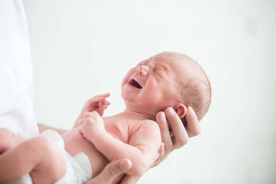 Portrait of a screaming newborn hold at hands Photograph by Fizkes