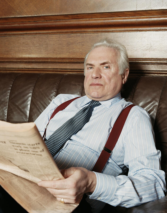 Portrait of a Senior Businessman Sitting on a Leather Sofa With a Newspaper Photograph by A J James