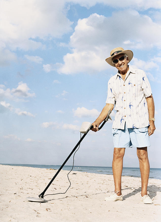 Portrait of a Senior Man Standing on a Beach Holding a Metal Detector Photograph by Digital Vision.