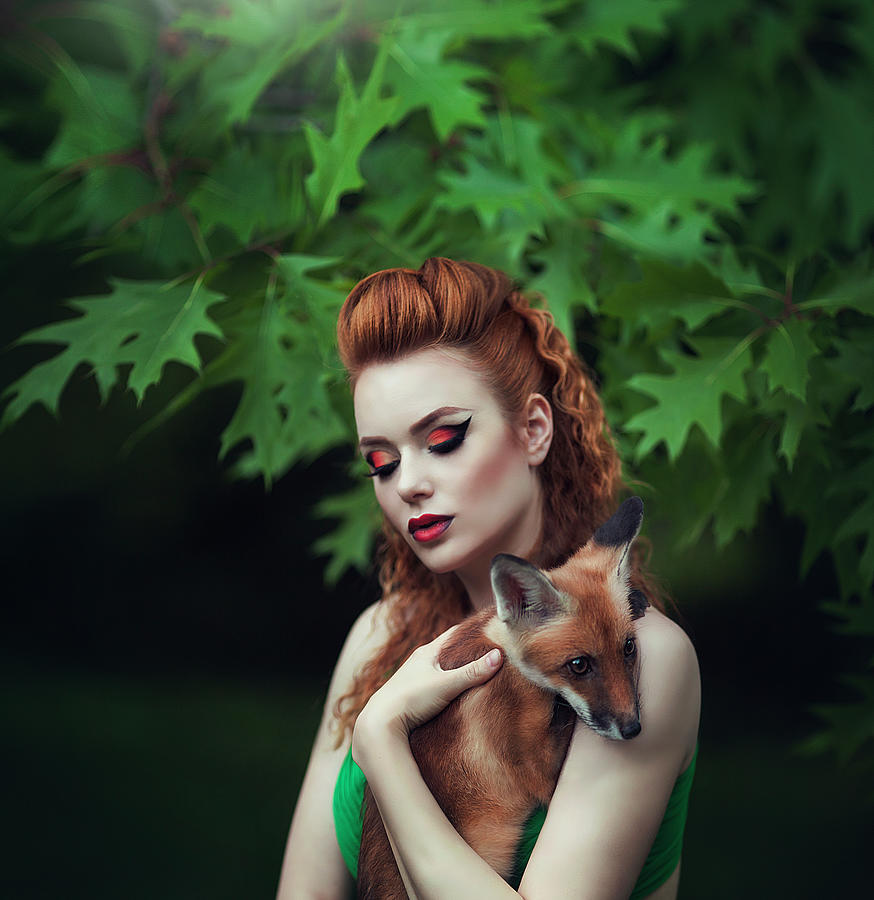 Portrait of a sensual red-haired girl in a green dress with a fox in a ...