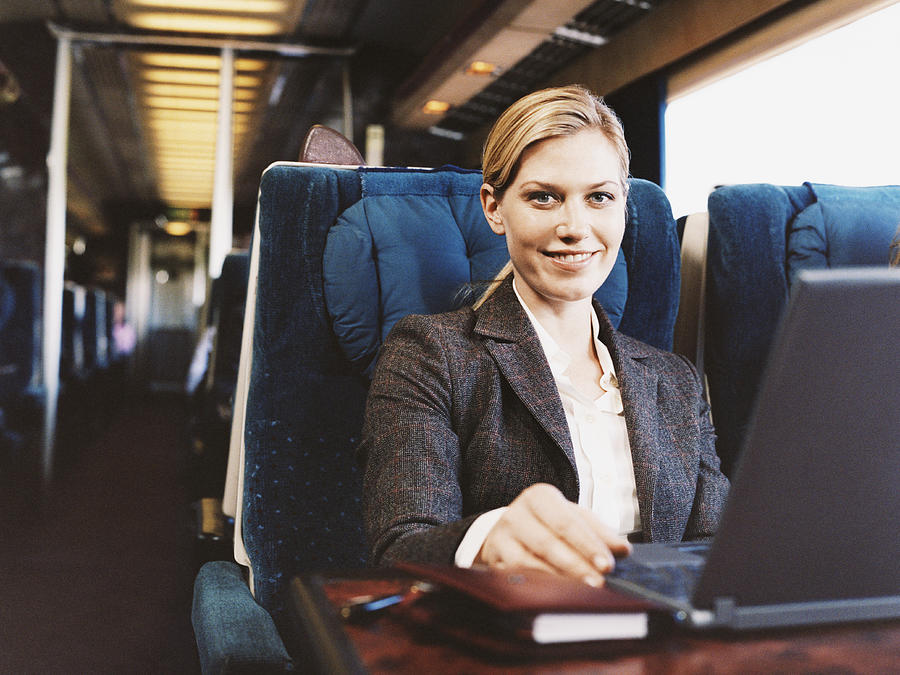 Portrait of a Smiling Businesswoman Sitting on a Passenger Train Photograph by Digital Vision.