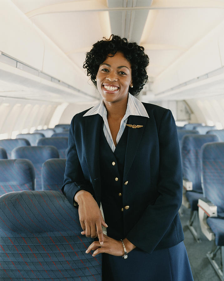 Portrait of a Smiling Female Flight Attendant on a Plane Photograph by Digital Vision.