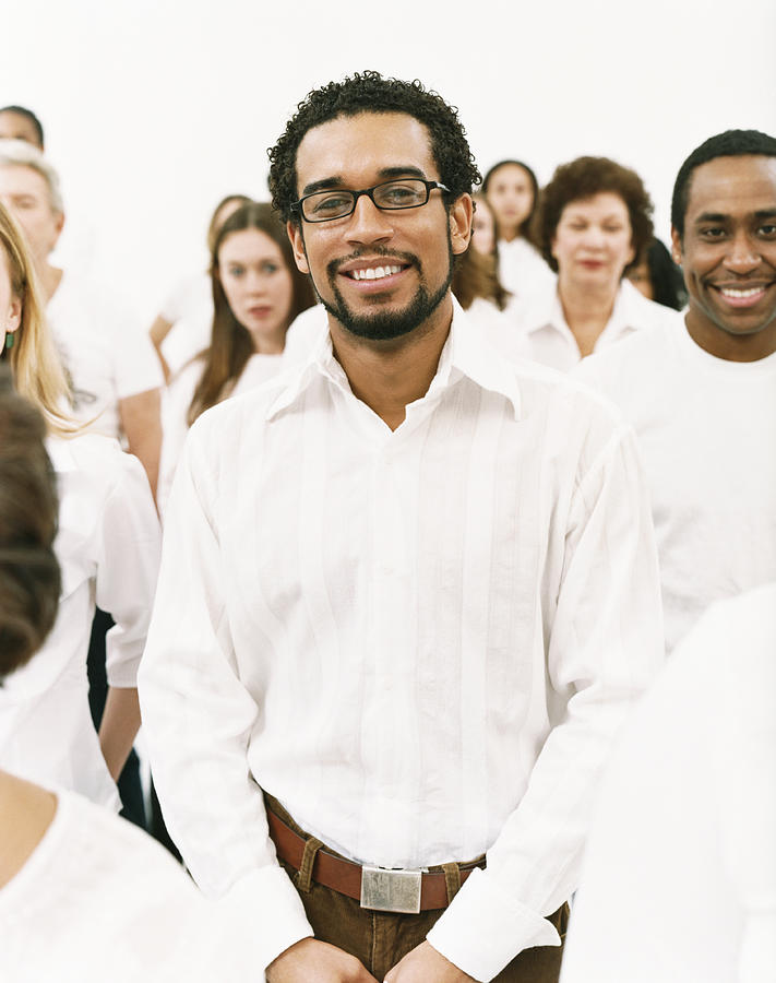 Portrait of a Smiling Man in a White Shirt Standing in a Crowd Photograph by Digital Vision.