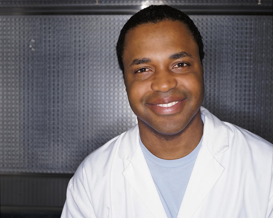 Portrait of a Smiling Man Wearing a Lab Coat Against a Grey Metallic Background Photograph by Noel Hendrickson