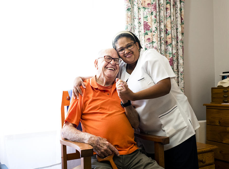 Portrait of a smiling senior man and nurse embracing Photograph by PixelCatchers