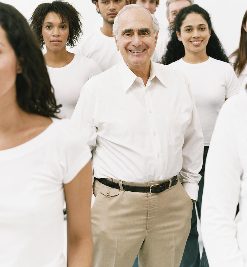 Portrait of a Smiling Senior Man in a White Shirt Standing in a Crowd Photograph by Digital Vision.