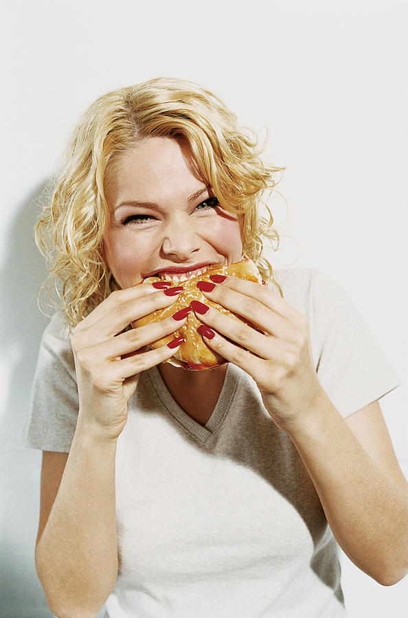 Portrait of a Smiling, Young Woman Eating a Hamburger Photograph by Digital Vision.