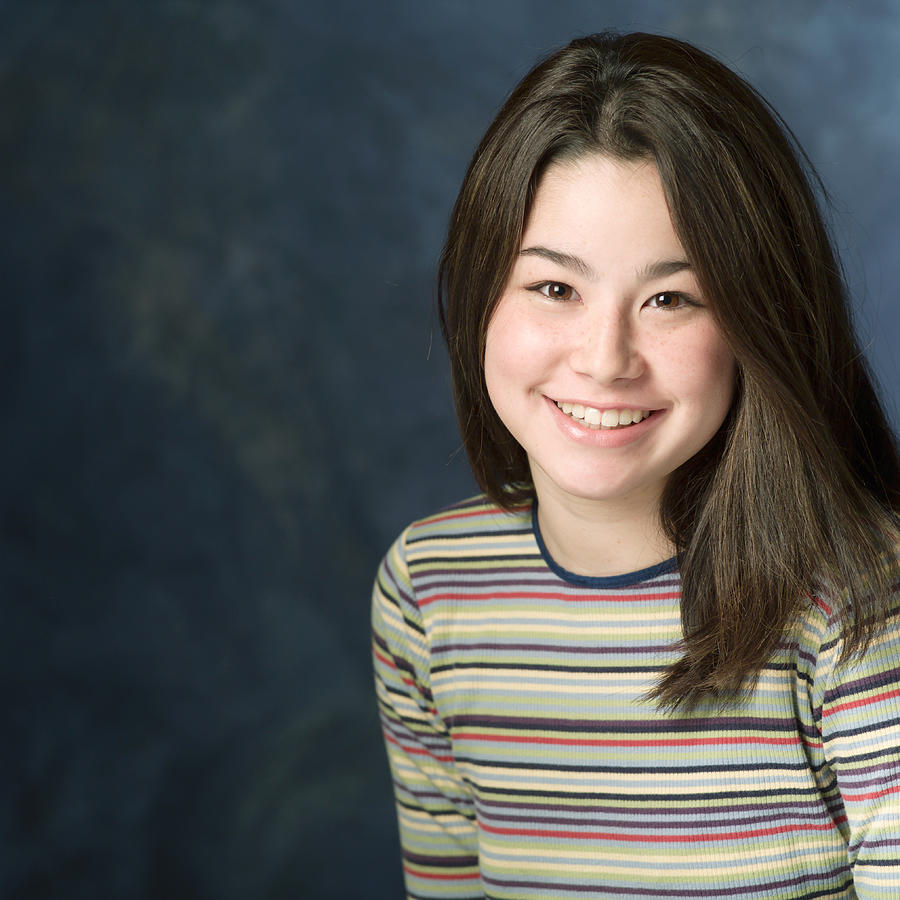 Portrait Of A Teenage Asian Girl In A Multi Colored Sweater As She Smiles At The Camera Photograph by Photodisc