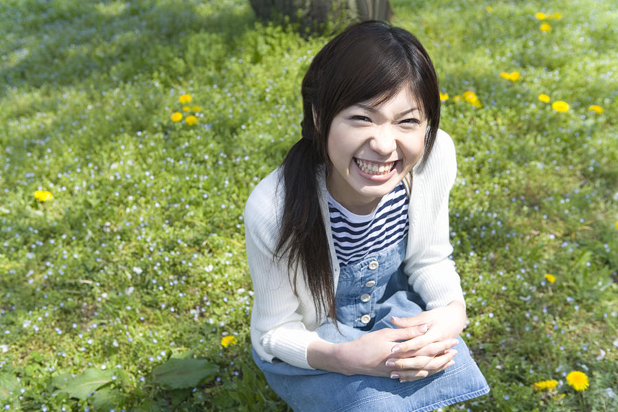 Portrait of a woman crouching down and looking at camera on field, high angle view, Japan Photograph by Daj