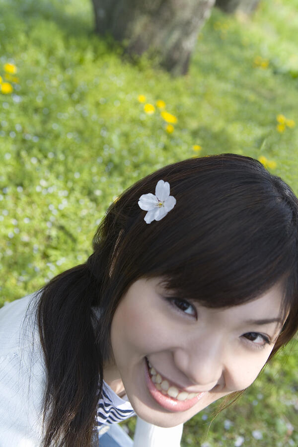 Portrait of a woman smiling and looking at camera, cherry flower on her hair, high angle view, Japan Photograph by Daj