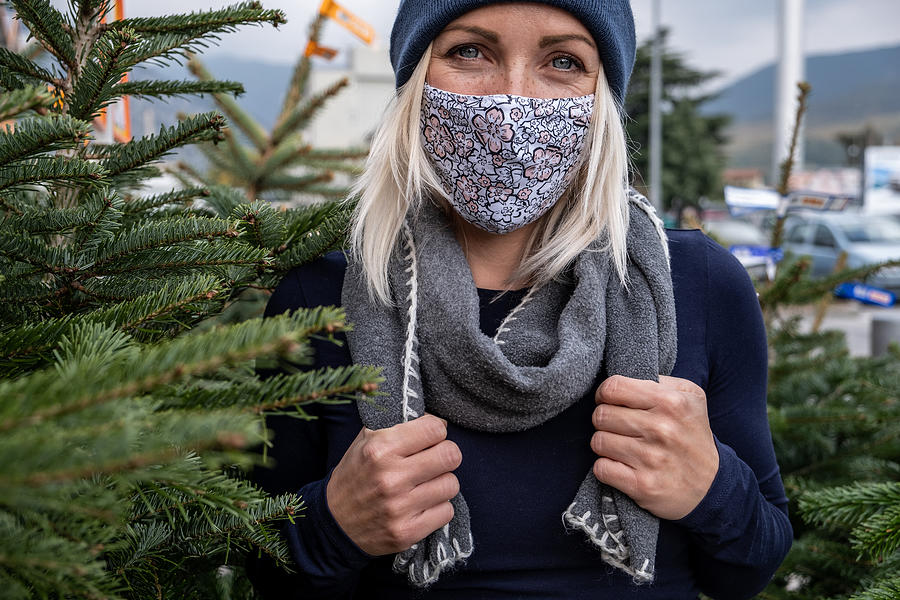 Portrait of a Woman with protective mask while selecting a Christmas tree at an outside market Photograph by AlenaPaulus