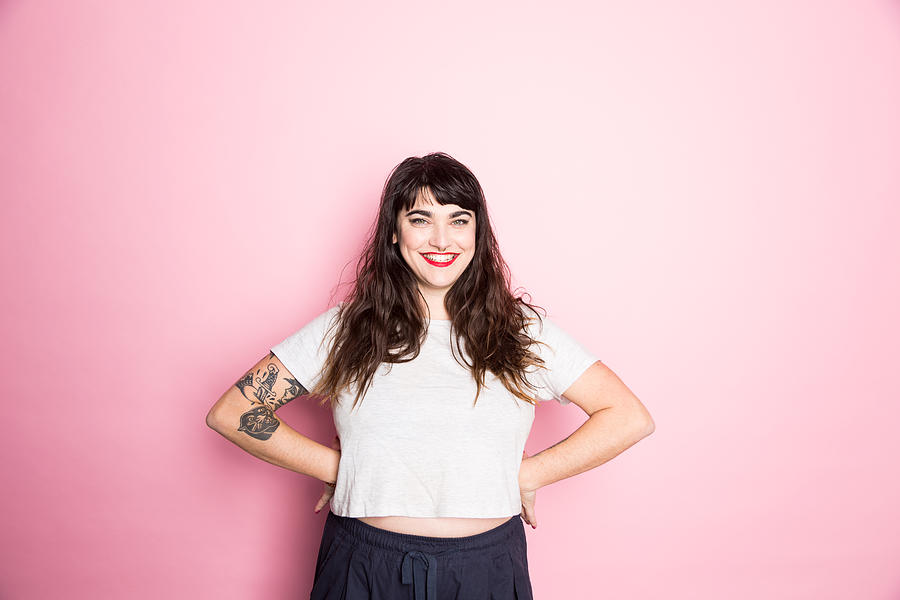 Portrait of a Woman with tattoos and red lipstick against a pink background Photograph by Jessie Casson