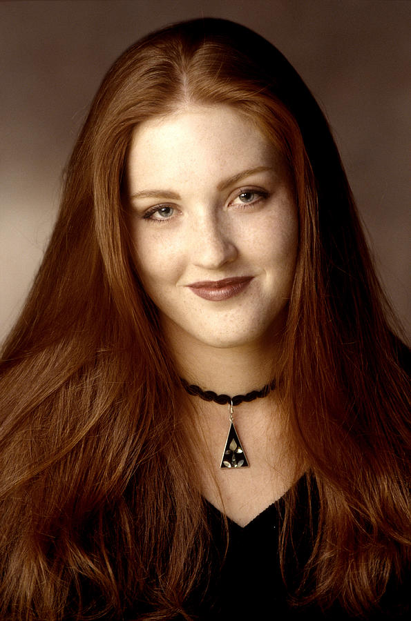 Portrait Of A Young Adult Redheaded Woman In A Black Sweater As She Smiles At The Camera Photograph by Photodisc