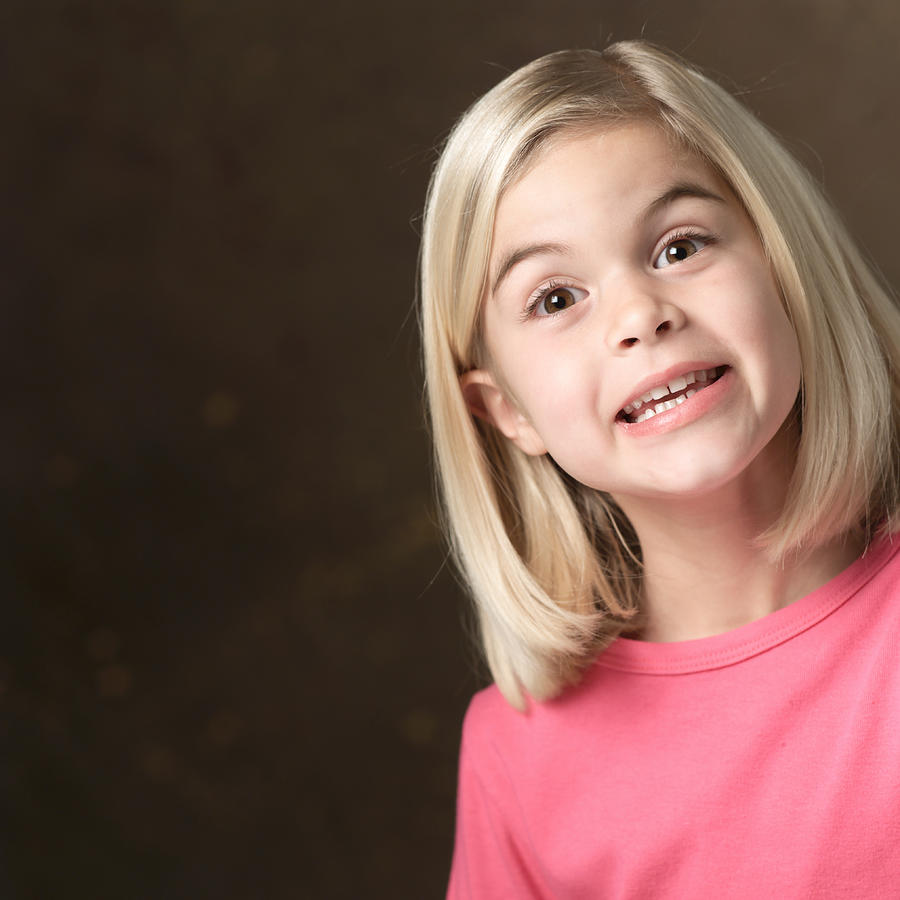 Portrait Of A Young Blonde Caucasian Girl In A Pink Shirt As She Smiles Big For The Camera Photograph by Photodisc