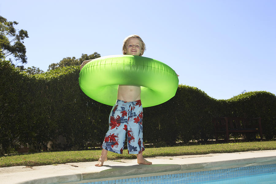 Portrait of a Young Boy Wearing a Rubber Ring Standing by a Swimming Pool Photograph by Digital Vision.