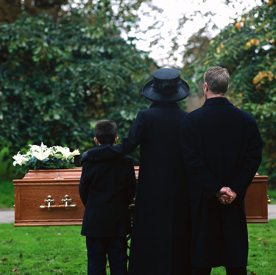 Portrait Of A Young Couple And Their Son Standing In A Cemetery Photograph by Stockbyte