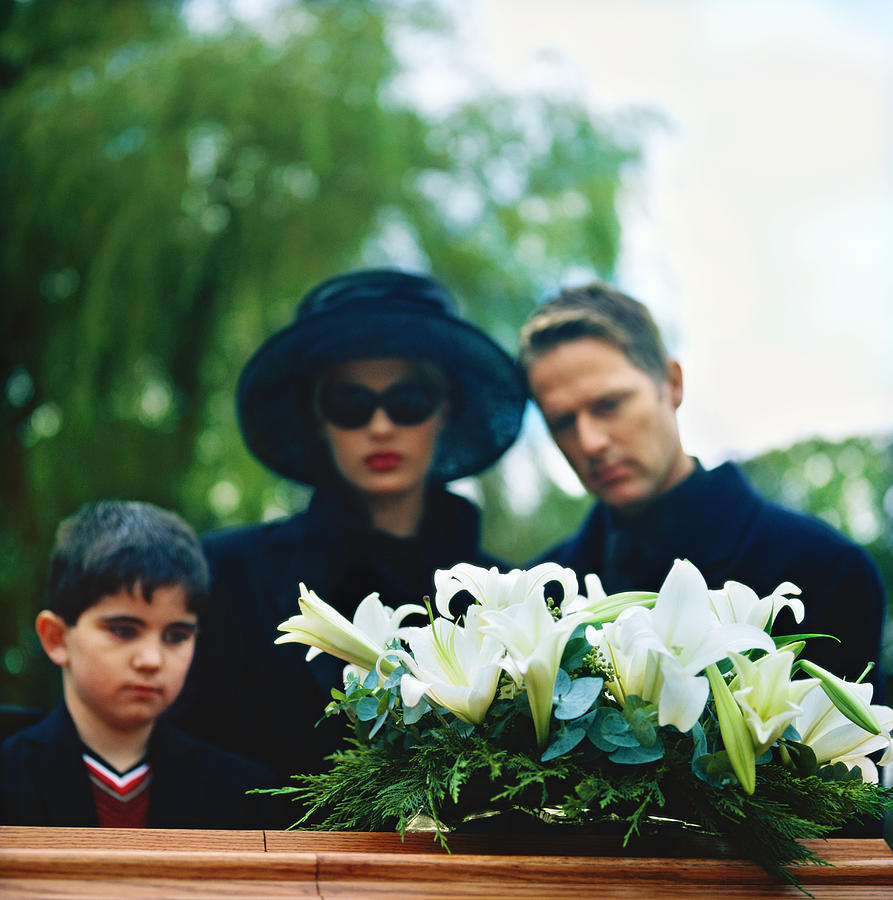Portrait Of A Young Couple And Their Son Standing Over A Coffin Photograph by Stockbyte