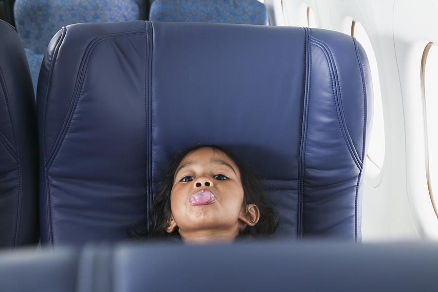 Portrait of a young girl sitting in a seat showing her tongue in an airplane Photograph by Colorblind Images LLC