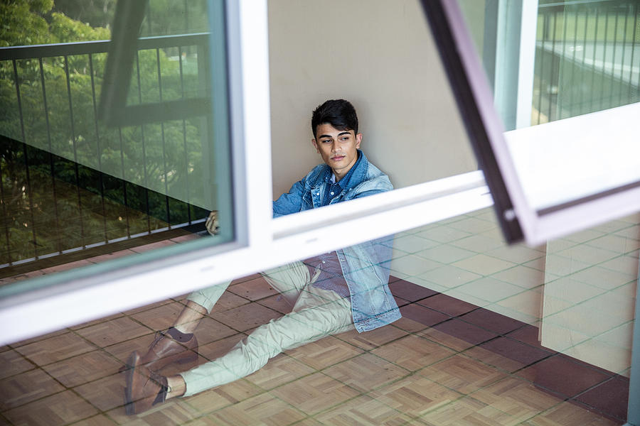 Portrait of a young man sitting at a wall and looking outside through window Photograph by Attila Csaszar