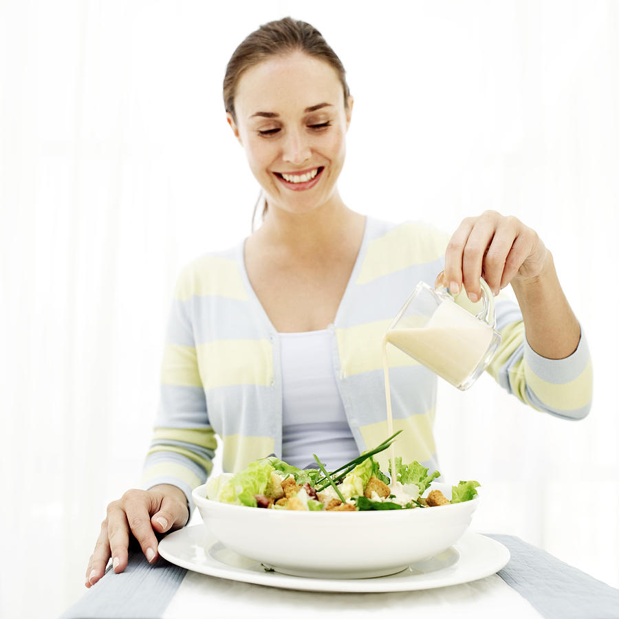 Portrait Of A Young Woman Dressing A Salad Photograph by Stockbyte