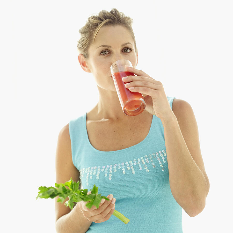 Portrait Of A Young Woman Drinking Tomato Juice And Holding A Celery Stick Photograph by Stockbyte