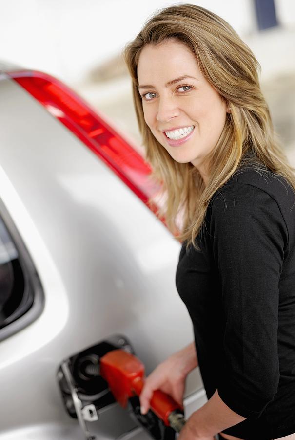 Portrait of a young woman refueling a car Photograph by Glowimages