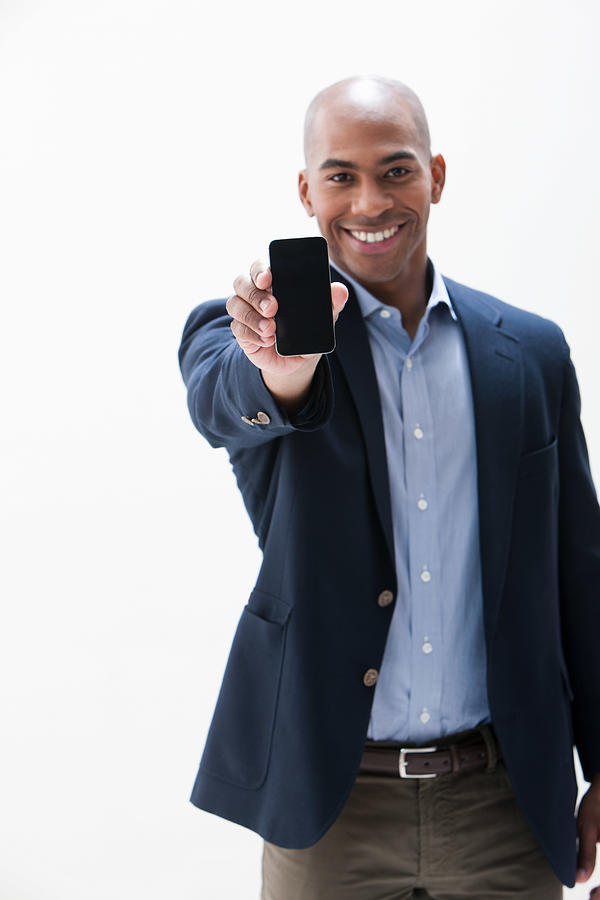 Portrait of African American man holding cellphone, studio shot Photograph by Image Source