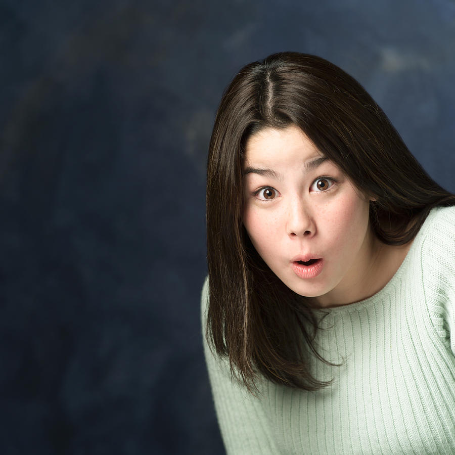 Portrait Of An Asian Teenage Girl In A Green Sweater As She Looks Very Surprised Photograph by Photodisc