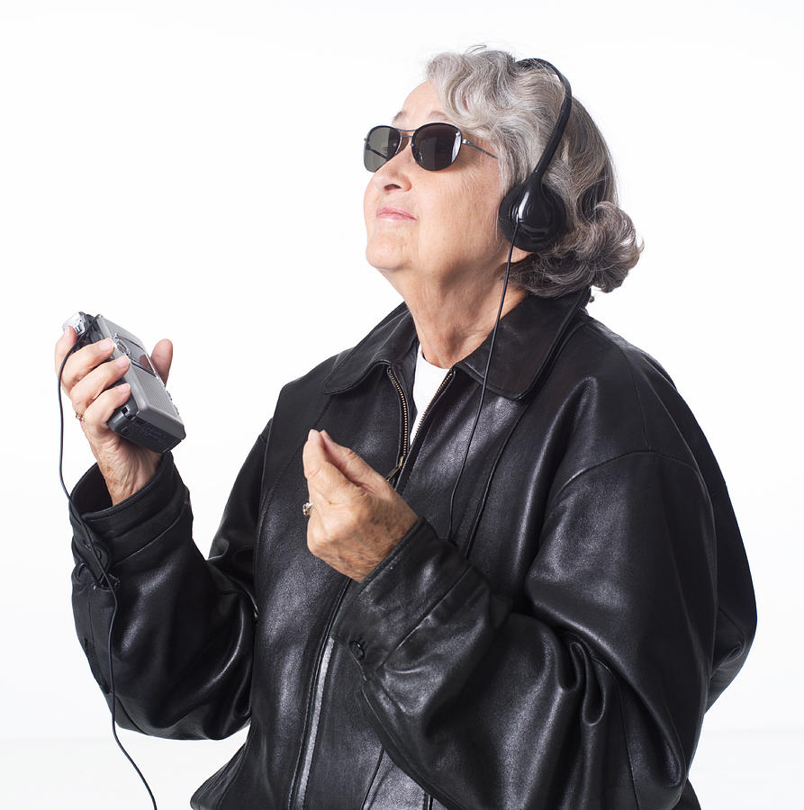 Portrait Of An Elderly Caucasian Woman In A Leather Jacket And Sunglasses As She Listens To Music Through Headphones Photograph by Photodisc