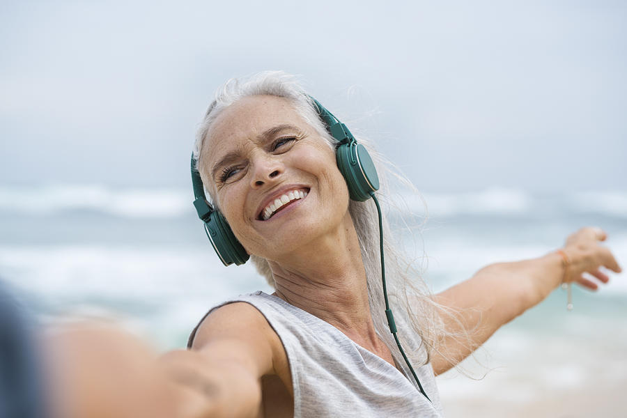 Portrait of beautiful smiling senior woman dancing on beach Photograph by Westend61