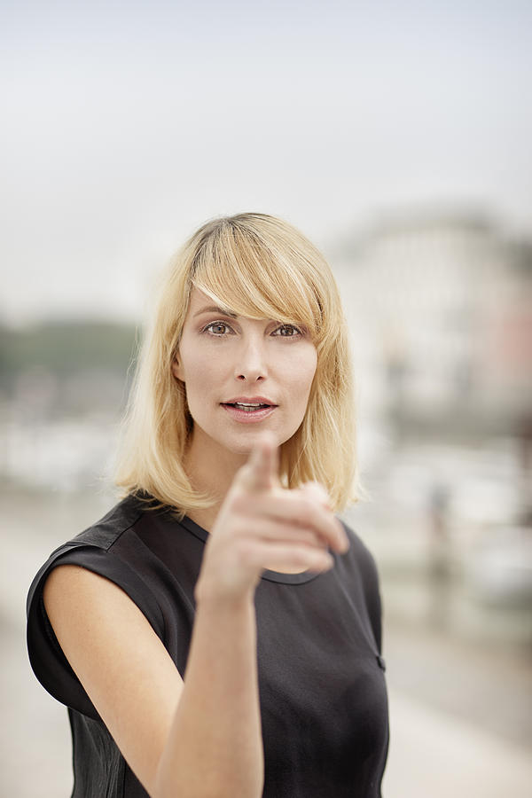 Portrait of blond woman pointing on viewer Photograph by Westend61