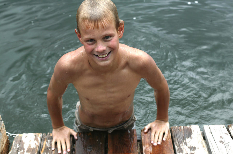 Portrait of boy (11-13) leaning on edge of pier, smiling Photograph by Vicky Kasala