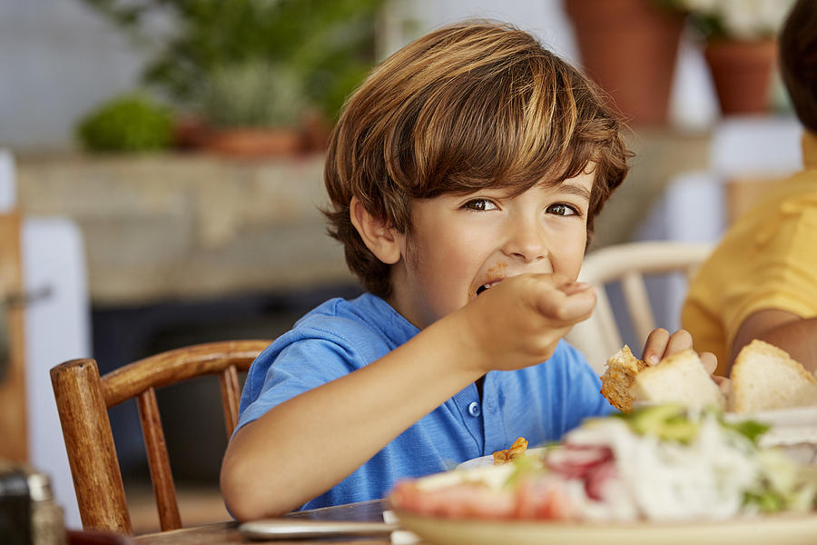 Portrait of boy eating food at table in house Photograph by Morsa Images