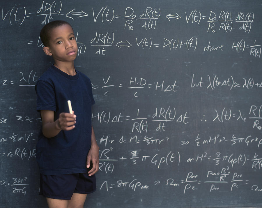 Portrait of boy holding chalk while standing in front of chalkboard Photograph by ER Productions Limited