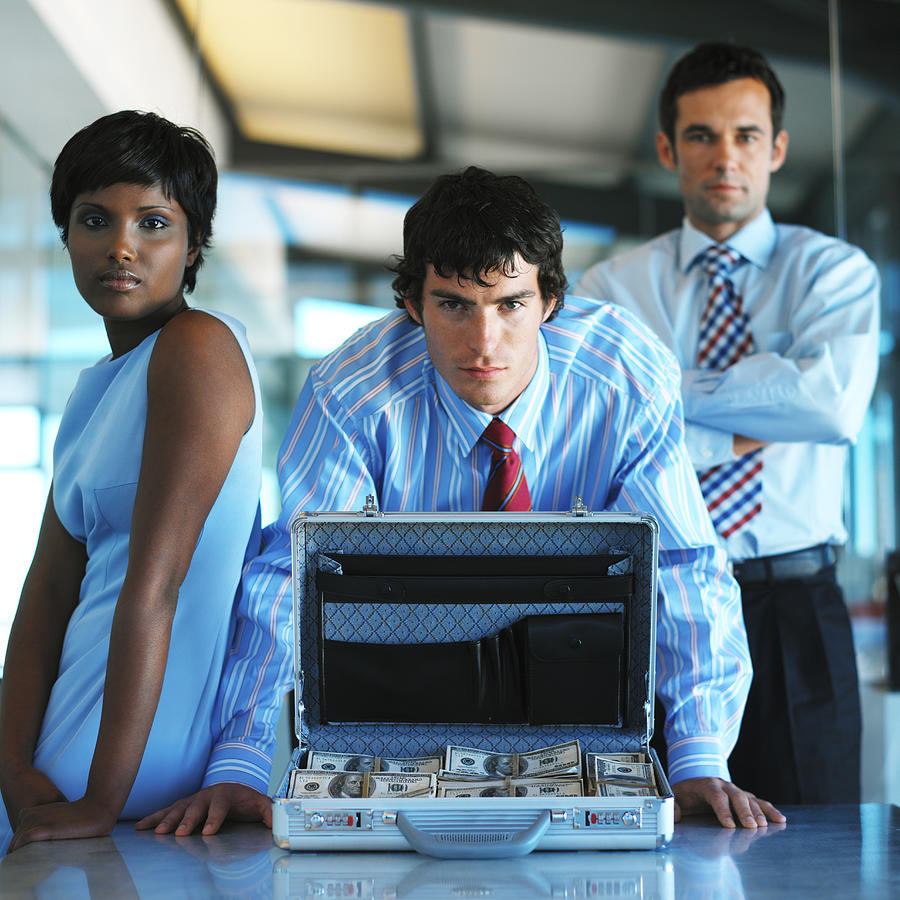 Portrait Of Business Executives Behind An Open Briefcase Full Of Money Photograph by Stockbyte