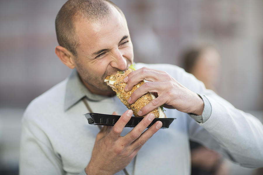 Portrait of businessman eating a sandwich at lunchtime Photograph by Westend61