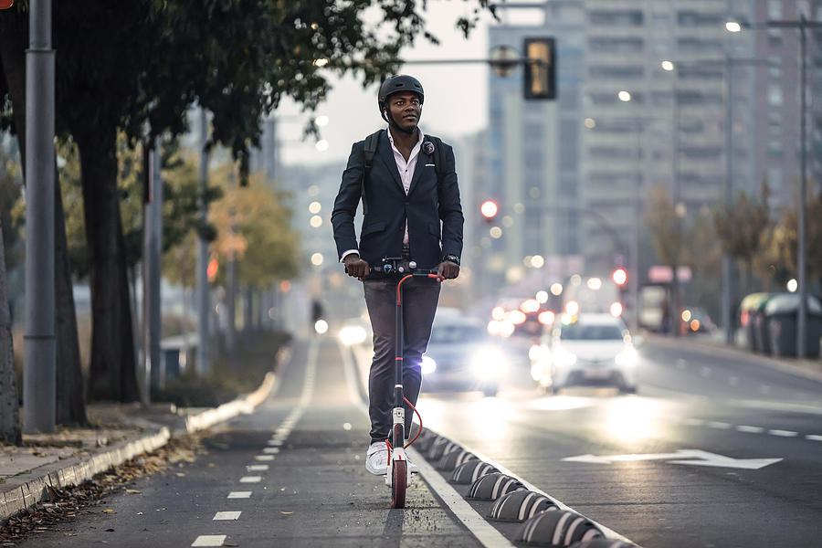 Portrait of businessman riding push scooter on bicycle lane in the evening Photograph by Westend61