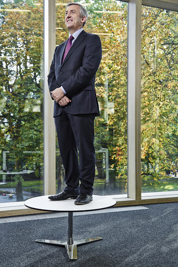 Portrait of businessman standing on table Photograph by Compassionate Eye Foundation/Dan Kenyon
