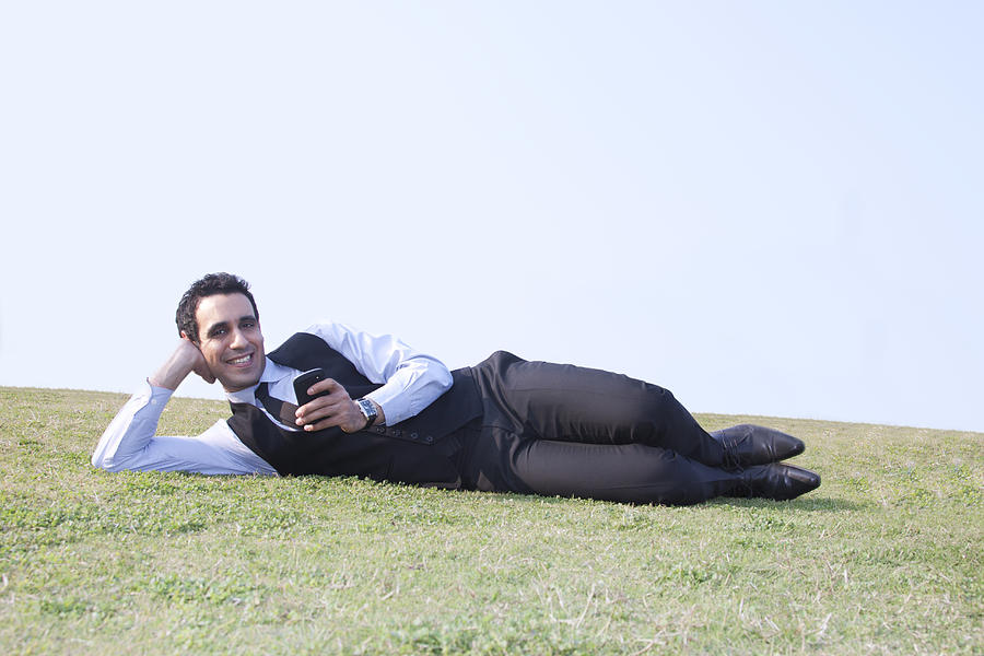 Portrait of businessman with mobile phone lying down , INDIA , DELHI Photograph by Sudipta Halder
