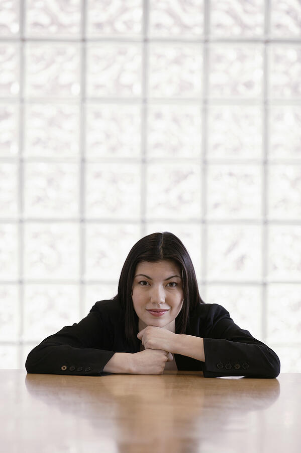 Portrait of businesswoman leaning on table Photograph by Comstock Images