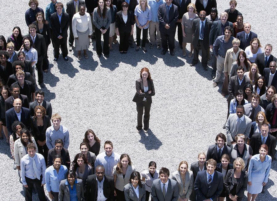Portrait of businesswoman standing at center of circle formed by business people Photograph by Martin Barraud