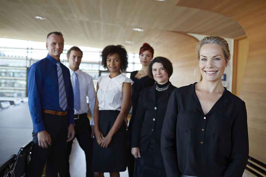 Portrait of businesswoman with coworkers in back Photograph by Klaus Vedfelt