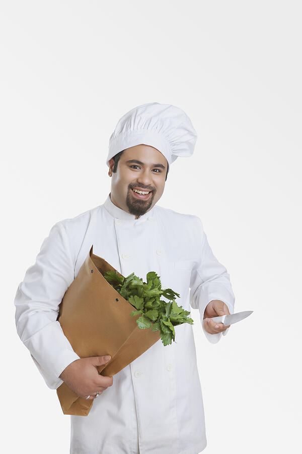 Portrait of chef with bag of vegetables and knife Photograph by IndiaPix/IndiaPicture