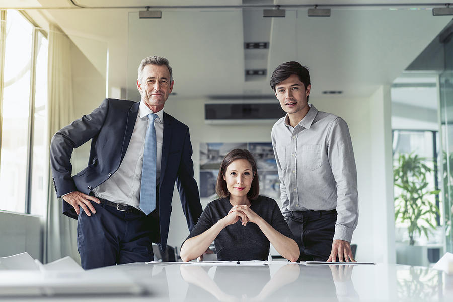 Portrait of confident business people at desk Photograph by Portra