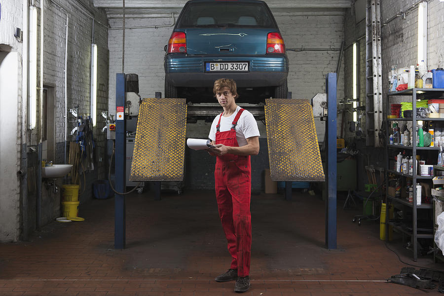 Portrait of confident mechanic holding clipboard at garage Photograph by Halfdark