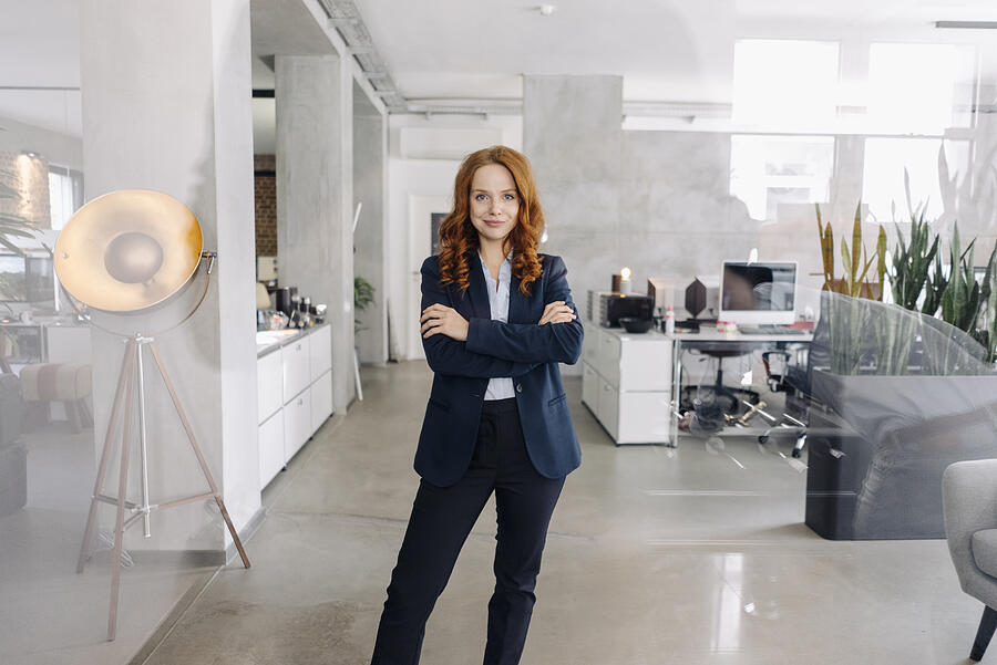 Portrait of confident redheaded businesswoman standing in office Photograph by Westend61