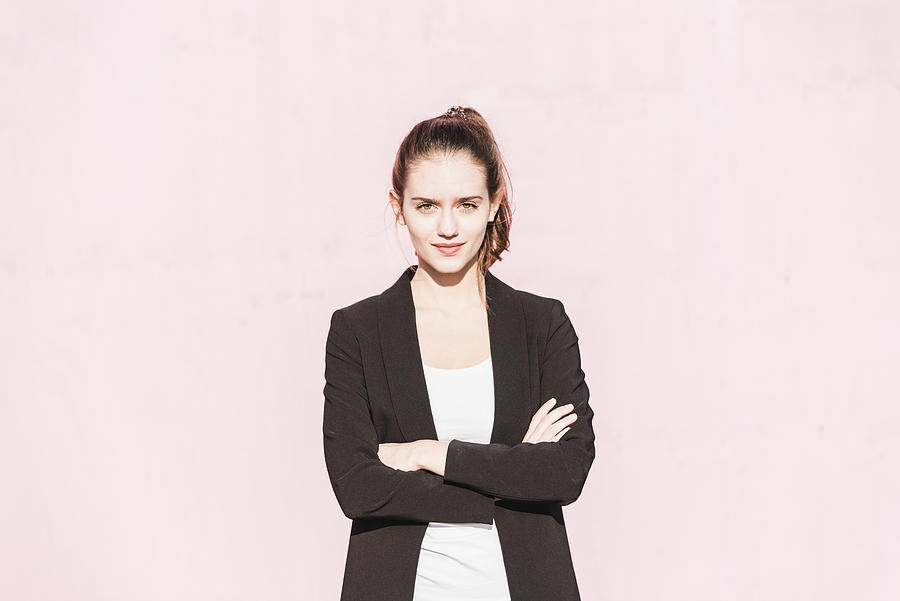 Portrait of confident young woman in front of pink wall Photograph by Westend61