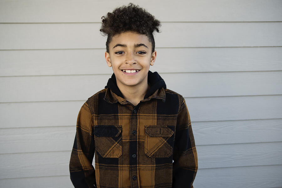 Portrait of cute mixed-race preteen boy outdoors. Photograph by Martinedoucet
