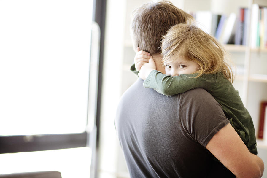 Portrait of daughter embracing father at home Photograph by Cavan Images